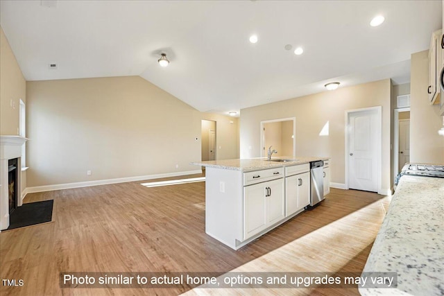 kitchen featuring a sink, a fireplace with flush hearth, vaulted ceiling, stainless steel dishwasher, and light wood finished floors