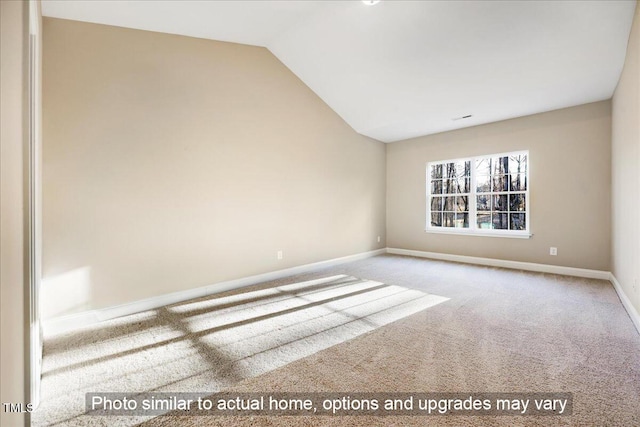 carpeted empty room featuring lofted ceiling and baseboards