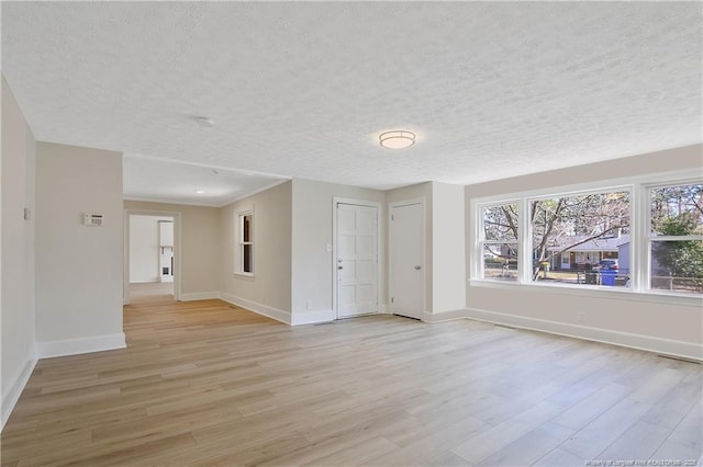 unfurnished room featuring light wood-style flooring, baseboards, and a textured ceiling