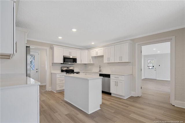 kitchen with light wood finished floors, light countertops, appliances with stainless steel finishes, white cabinets, and a sink