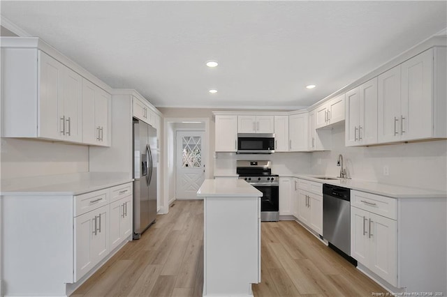 kitchen with light wood-style floors, appliances with stainless steel finishes, a sink, and a center island