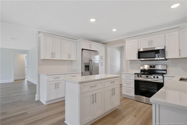 kitchen with stainless steel appliances, light countertops, light wood-style floors, white cabinetry, and a kitchen island