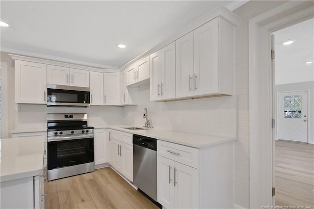 kitchen with light wood-style floors, white cabinetry, appliances with stainless steel finishes, and a sink