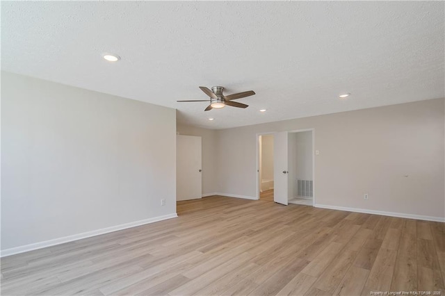 empty room with light wood-style flooring, baseboards, and a textured ceiling