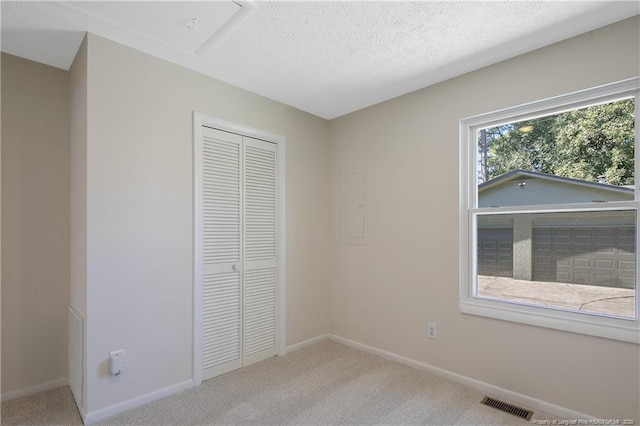 unfurnished bedroom with a textured ceiling, a closet, visible vents, and carpet flooring