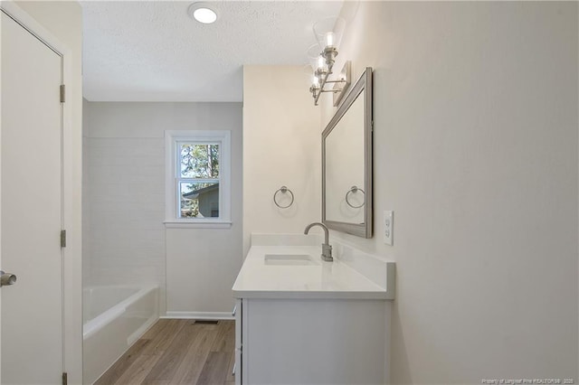 full bathroom featuring vanity, visible vents, a textured ceiling, and wood finished floors