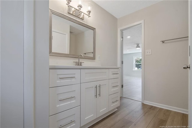 bathroom featuring ceiling fan, vanity, baseboards, and wood finished floors