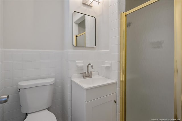 full bathroom featuring toilet, vanity, tile walls, wainscoting, and a shower stall