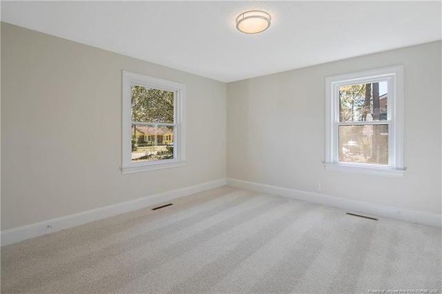 carpeted empty room featuring visible vents and baseboards