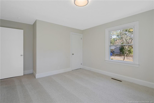 spare room with baseboards, visible vents, and light colored carpet