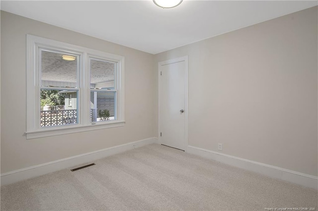 unfurnished room with light carpet, visible vents, and baseboards