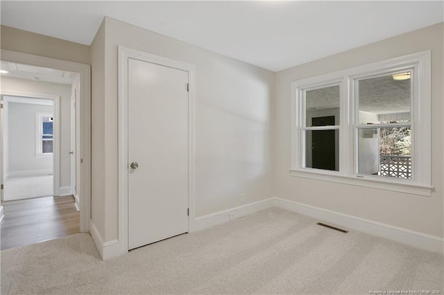 empty room featuring carpet, visible vents, and baseboards