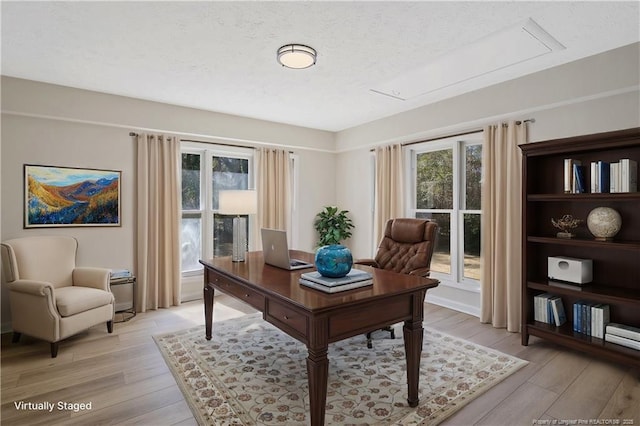 office space with light wood-style floors, a textured ceiling, and a wealth of natural light