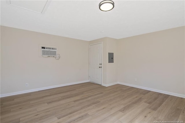 spare room featuring light wood-type flooring, electric panel, and baseboards