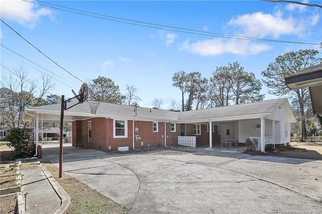 view of front of property with driveway, crawl space, an attached carport, and brick siding