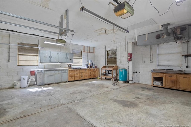 garage featuring concrete block wall, a workshop area, and a garage door opener