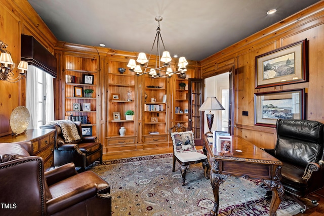 office featuring built in shelves, wood walls, and an inviting chandelier