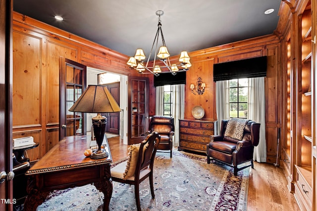 office space with wood walls, a notable chandelier, and wood finished floors