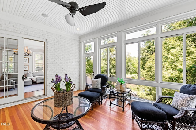 sunroom / solarium with ceiling fan with notable chandelier and wood ceiling