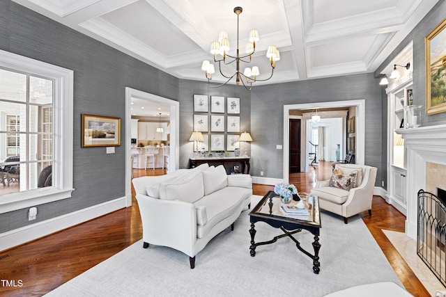 living area featuring baseboards, coffered ceiling, a tiled fireplace, and wood finished floors