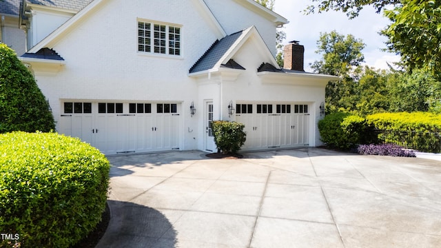 exterior space featuring driveway, brick siding, and a chimney