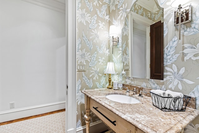 bathroom featuring baseboards, ornamental molding, vanity, and wallpapered walls