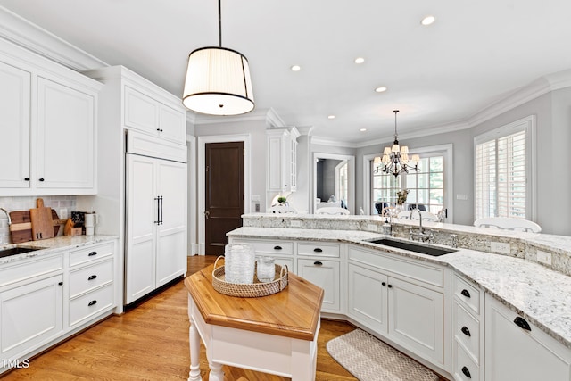 kitchen with light wood-type flooring, a sink, white cabinetry, and crown molding