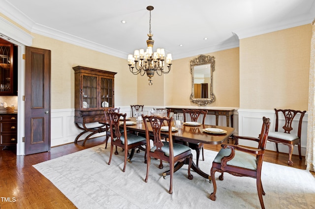 dining space featuring a chandelier, recessed lighting, a wainscoted wall, wood finished floors, and crown molding