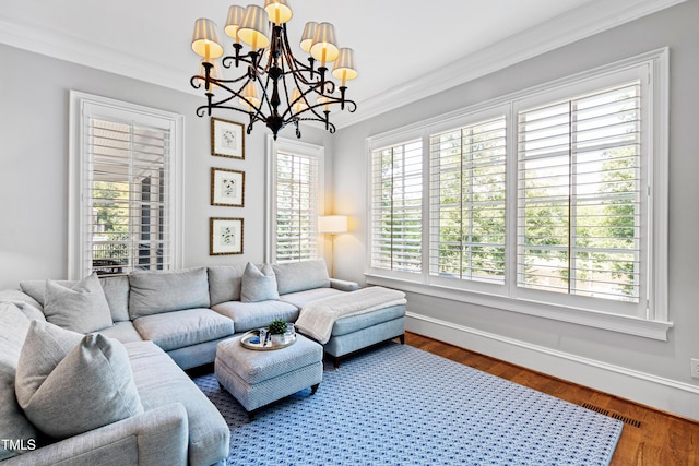 living area featuring a chandelier, wood finished floors, visible vents, baseboards, and crown molding