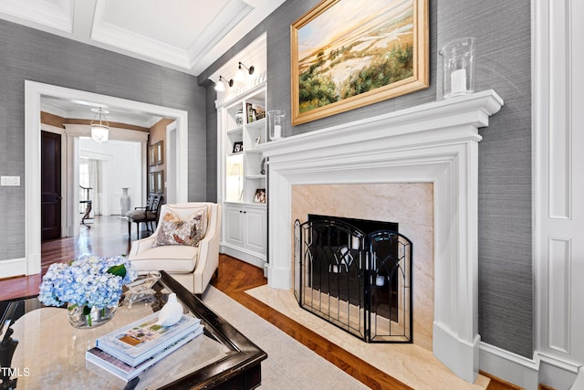 living room with wallpapered walls, built in features, a premium fireplace, wood finished floors, and crown molding