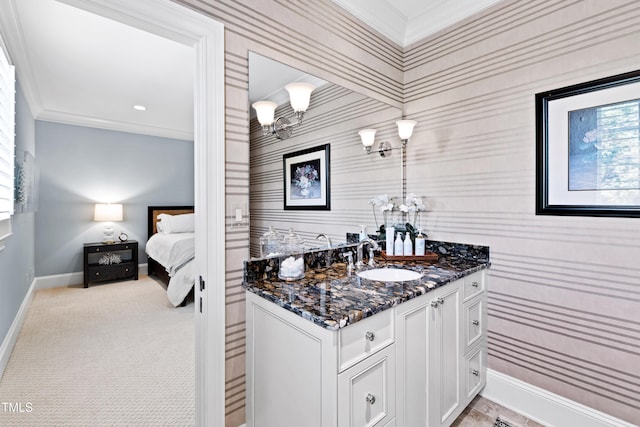 bathroom with an accent wall, vanity, baseboards, ornamental molding, and wallpapered walls