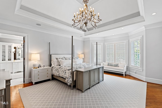 bedroom with a tray ceiling, light wood-style flooring, an inviting chandelier, ornamental molding, and baseboards