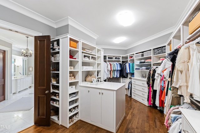 walk in closet with dark wood-style floors and an inviting chandelier