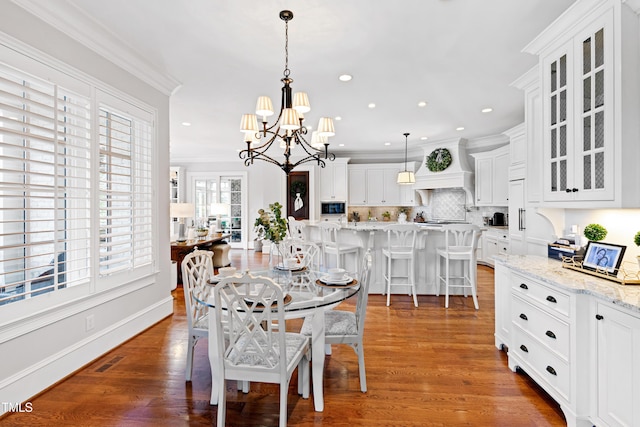 dining room with visible vents, crown molding, a notable chandelier, and wood finished floors