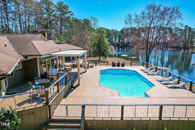 view of swimming pool with a patio, area for grilling, a water view, fence, and a fenced in pool