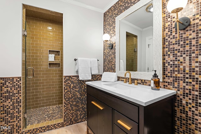 full bath with wood finished floors, tile walls, ornamental molding, wainscoting, and a shower stall