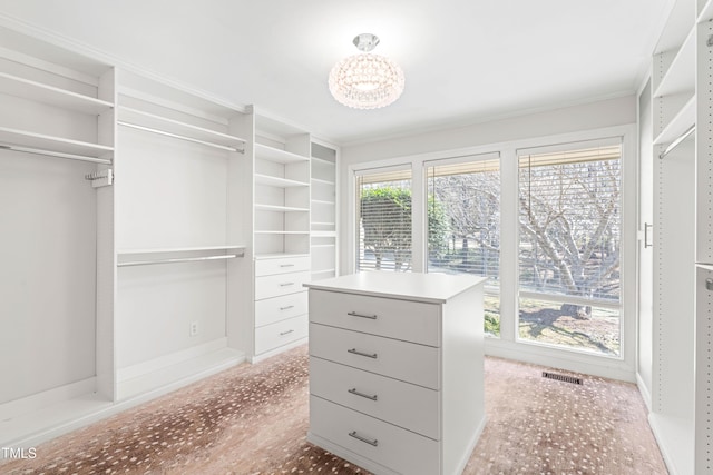 spacious closet featuring visible vents and a notable chandelier