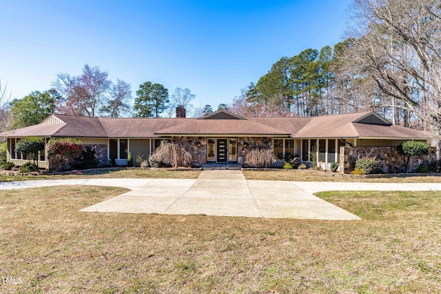 ranch-style house with concrete driveway, french doors, a chimney, and a front yard