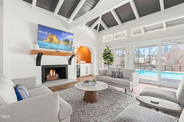 living area with wooden ceiling, a warm lit fireplace, lofted ceiling with beams, and wood finished floors