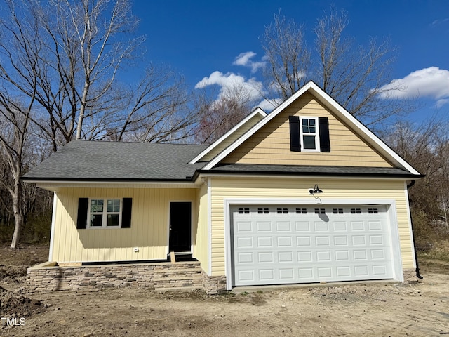 view of front of home with an attached garage and a shingled roof