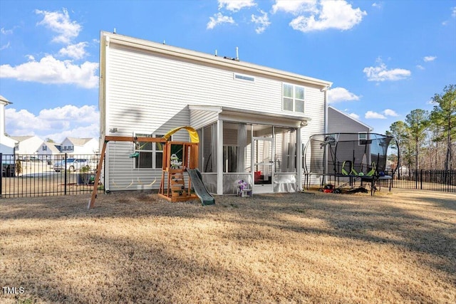 rear view of house featuring a trampoline, a sunroom, a fenced backyard, and a yard