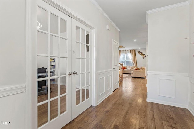 hall with french doors, a wainscoted wall, crown molding, and wood finished floors