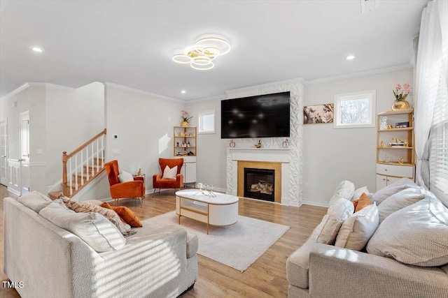 living room featuring ornamental molding, a large fireplace, stairway, and wood finished floors