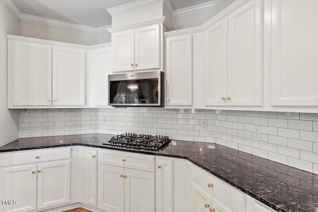 kitchen featuring gas cooktop, white cabinets, decorative backsplash, stainless steel microwave, and crown molding