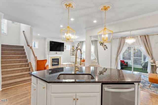 kitchen featuring light wood finished floors, a fireplace, open floor plan, and a sink