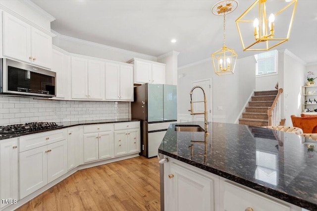 kitchen with gas cooktop, a sink, ornamental molding, freestanding refrigerator, and stainless steel microwave