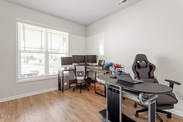 office space with light wood-style flooring, visible vents, and baseboards