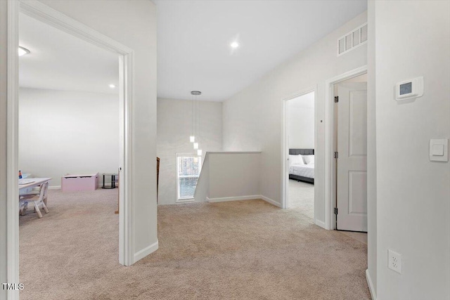 hall featuring carpet floors, baseboards, visible vents, and an upstairs landing