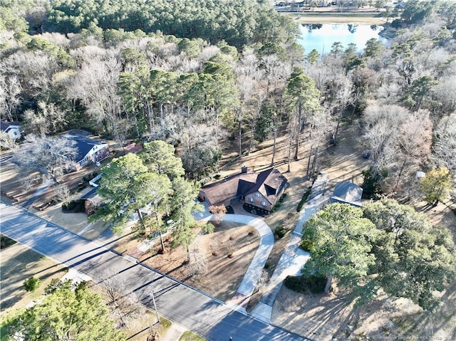 birds eye view of property with a water view and a wooded view