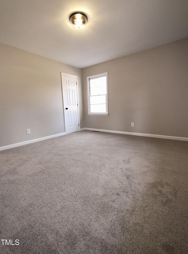 unfurnished room featuring carpet, baseboards, and a textured ceiling